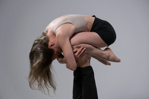 Woman performing a fluid stretching movement in a minimalist studio.
